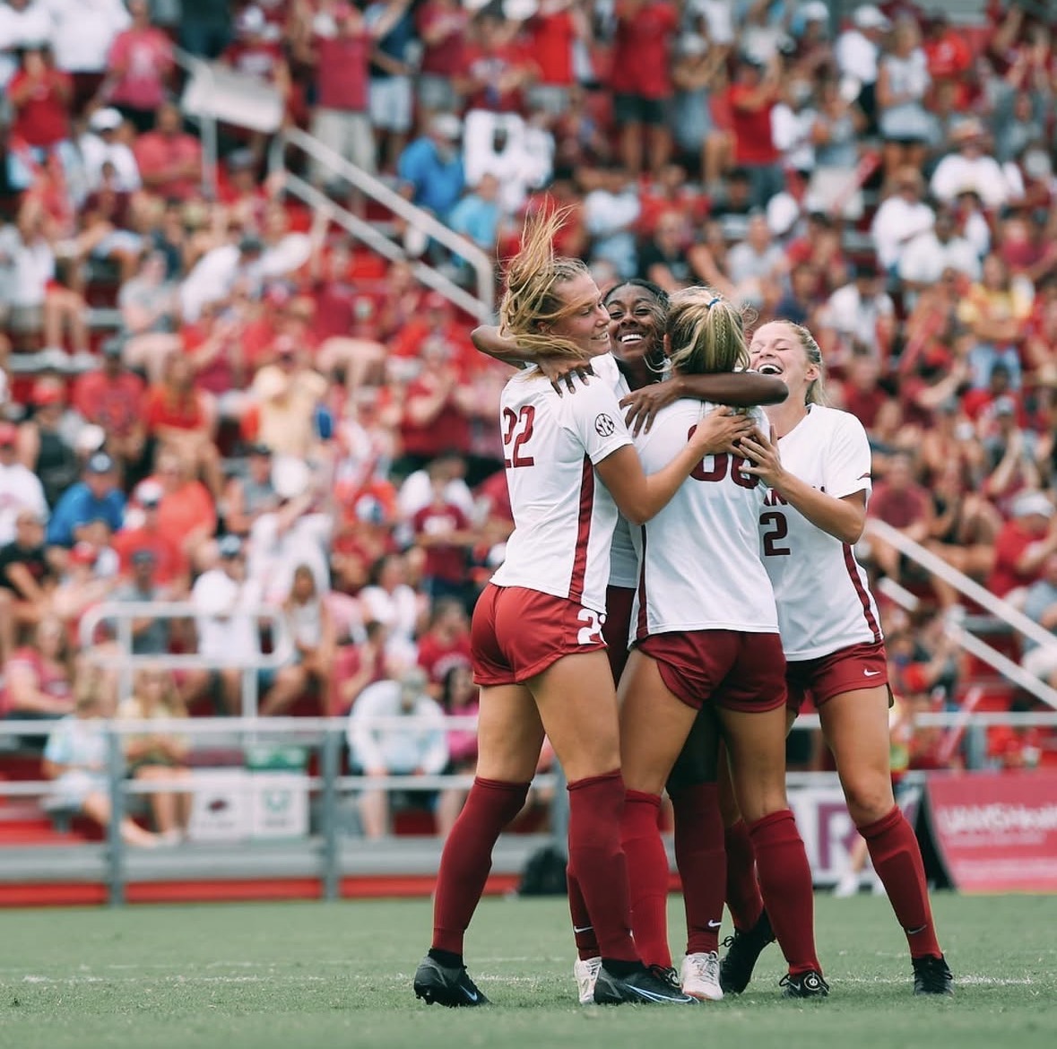 Ainsley Erzen celebrating a goal with her Arkansas teammates in a packed stadium